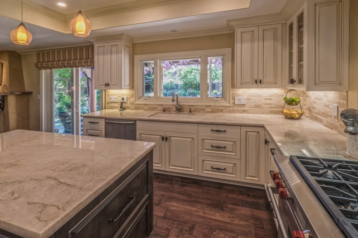 Sink run below the garden window, stone counters against a travertine backsplash