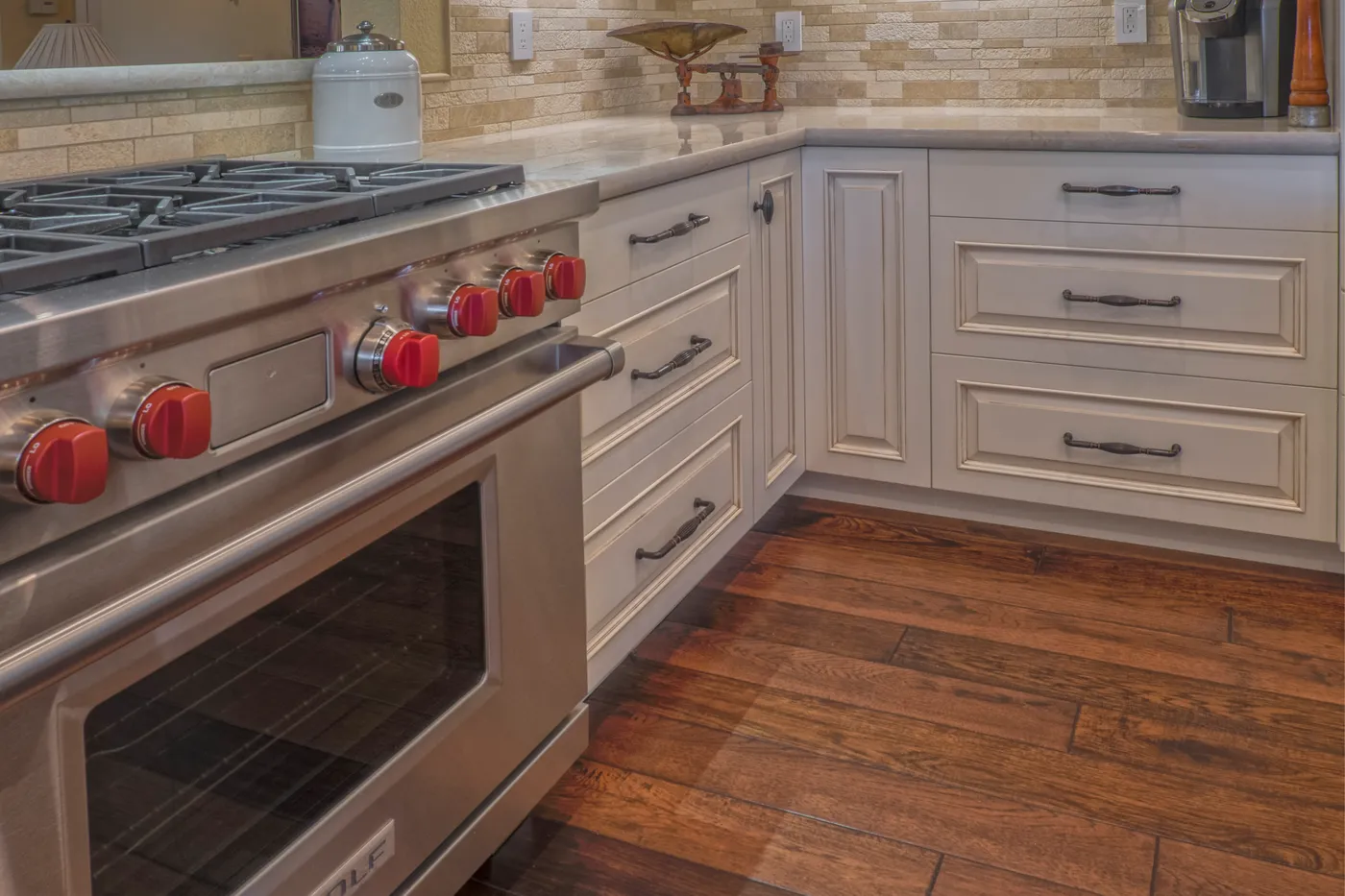 Stainless range with red control knobs set into the cream cabinetry