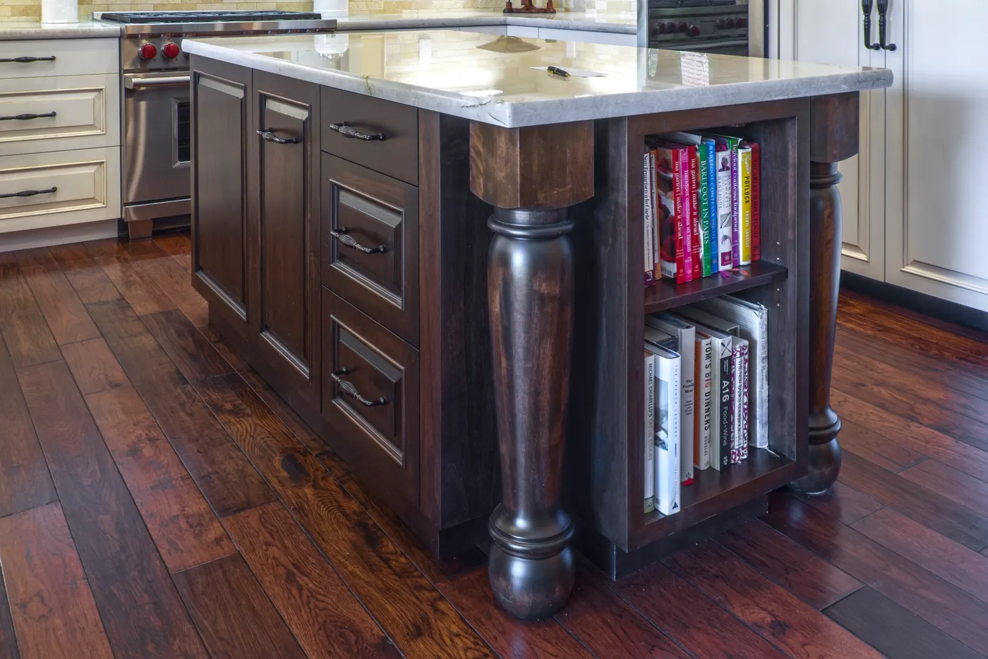 End of the walnut island, turned legs beside open cookbook shelves