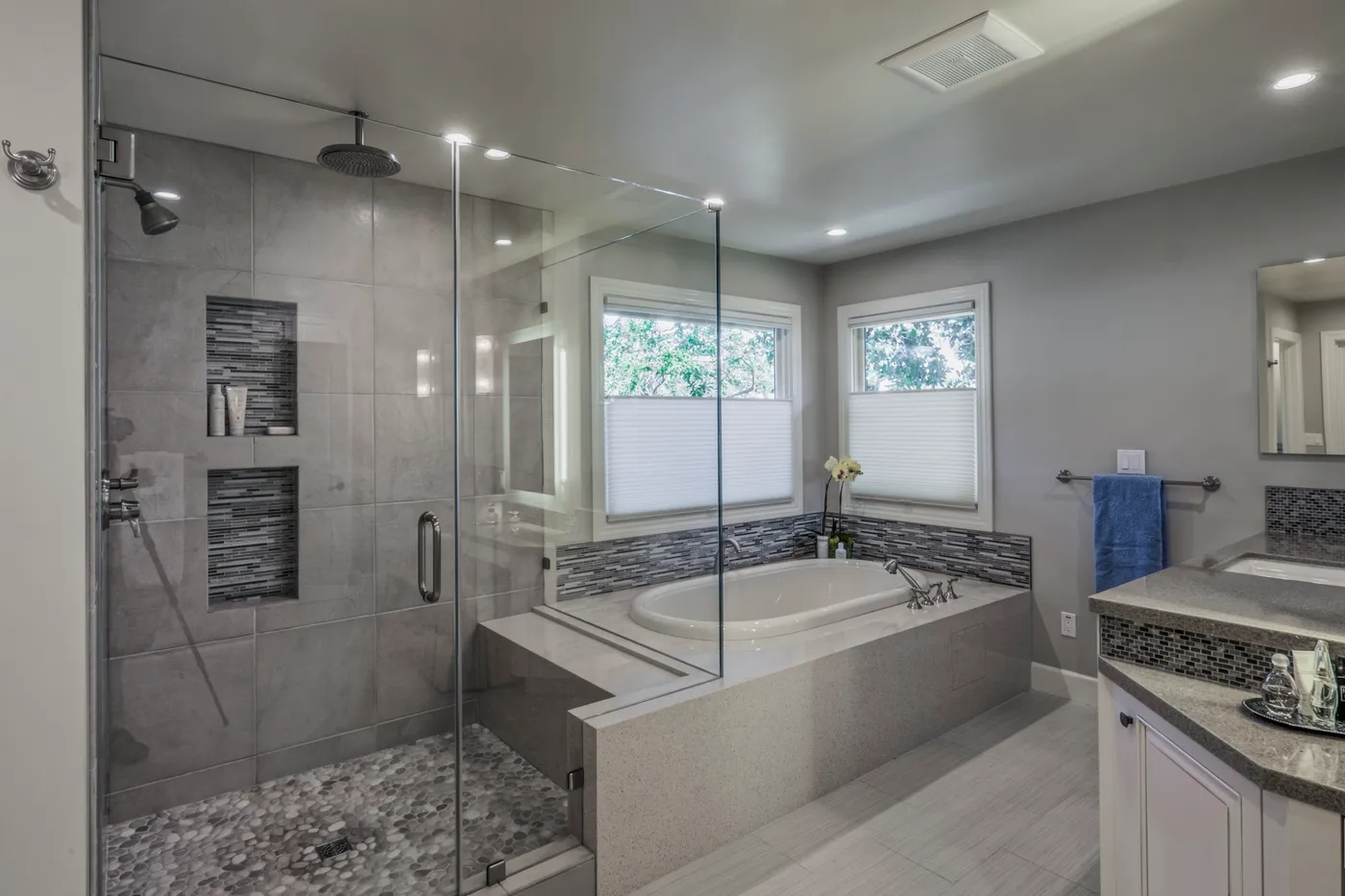 Glass shower beside the tub, mosaic tile banding the surround